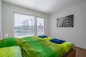 - une chambre avec un lit doté d'une couette verte et d'une fenêtre dans l'établissement Apartmány Pustiměř, à Pustiměř