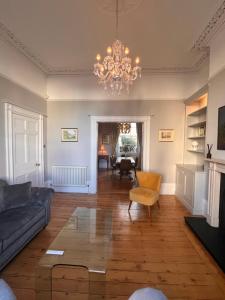 a living room with a couch and a chandelier at No2 Clarence grade II Regency townhouse short walk to racecourse and town centre in Cheltenham