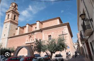eine Kirche mit einem Uhrturm und Autos, die auf einer Straße geparkt sind in der Unterkunft Apartamento en Almenara a 4 KM de la playa in Almenara