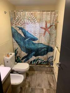 a bathroom with a dolphin shower curtain and a toilet at Lujo, PS5 cerca de las mejores Bodegas + desayuno in Ciudad Lujan de Cuyo