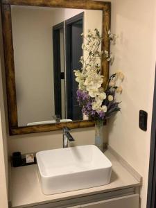 a bathroom sink with a mirror and a vase of flowers at Lujo, PS5 cerca de las mejores Bodegas + desayuno in Ciudad Lujan de Cuyo