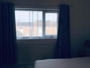 a bedroom with a window with blue curtains and a bed at Jessy Joe in Bournemouth