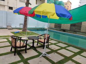 Rainbow International Hotel Airport Zone Shamshabad في شامشاباد: طاولة وكراسي تحت مظلة بجوار مسبح