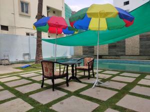 薩姆沙巴德的住宿－Rainbow International Hotel Airport Zone Shamshabad，一张桌子,两把椅子和两把五彩缤纷的雨伞