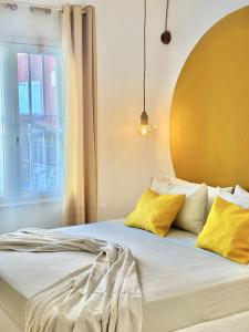 um quarto com uma cama com almofadas amarelas e uma janela em Boutique Apartments Ibiscus em Santa Maria