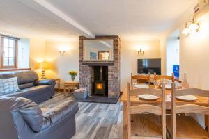 sala de estar con sofá, mesa y chimenea en Yr Eifl Cottage, en Llanfairpwllgwyngyll