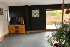 a living room with a television on a wooden dresser at NIDS SAUVAGES - Villa unique en baie de Somme in Saint-Quentin-en-Tourmont