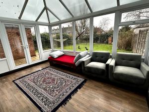 a living room with two chairs and a red couch at Spacious House in Hertfordshire in Borehamwood
