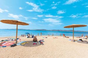 um grupo de pessoas em uma praia com guarda-sóis em Apartment Dora em Zadar
