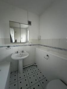 a bathroom with a sink and a toilet and a mirror at Spacious House in Hertfordshire in Borehamwood
