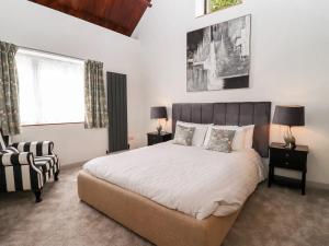 a bedroom with a large bed and a chair at Mayfield Cottage in Malmesbury