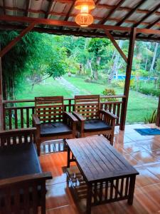 a porch with benches and a table and a view of a park at De Casa Ananda Nusa Penida in Nusa Penida