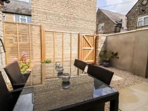 een patio met een tafel en stoelen en een hek bij Mayfield Cottage in Malmesbury