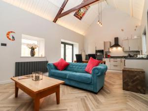 a living room with a blue couch and a table at Mayfield Cottage in Malmesbury