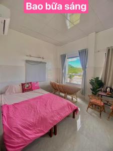 ein Schlafzimmer mit einem rosa Bett, einem Tisch und einem Fenster in der Unterkunft Homestay Tuyết Trinh in Nha Trang