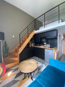 a living room with a blue couch and a staircase at Une fenêtre sur l océan, Studio duplex dans résidence de standing avec piscine et vue sur mer in Le Croisic