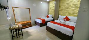 Habitación de hotel con 2 camas y espejo en OYO 1063 Manuela's Suites en Puerto Princesa