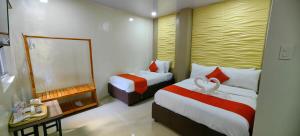 a hotel room with two beds and a mirror at OYO 1063 Manuela's Suites in Puerto Princesa City