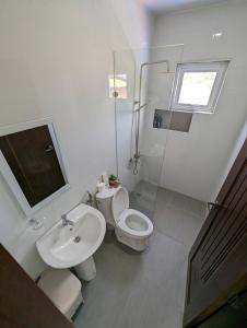 a white bathroom with a toilet and a sink at OYO 1063 Manuela's Suites in Puerto Princesa City