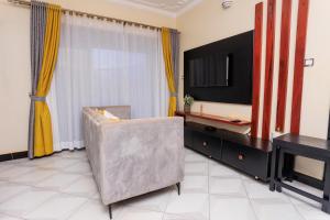 ein Wohnzimmer mit einem Stuhl und einem TV in der Unterkunft Greenwoods Apartments in Kampala