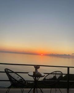 dwa krzesła i stół na balkonie z widokiem na zachód słońca w obiekcie Panorama Sarpi 029 w mieście Batumi