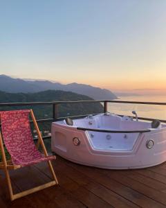 a tub and a chair on a deck with a view at Panorama Sarpi 029 in Batumi