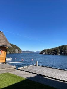 a dock on a lake with a house at Cozy ground floor apartment in nature, by driving 300 metres of gravel road on top of the hill in Lunde