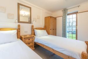 2 camas en una habitación con espejo y ventana en Elidir Cottage, en Llanfairpwllgwyngyll