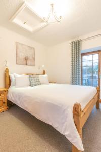 Un dormitorio con una gran cama blanca y una ventana en Elidir Cottage, en Llanfairpwllgwyngyll