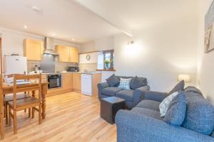 sala de estar con 2 sofás azules y cocina en Elidir Cottage, en Llanfairpwllgwyngyll