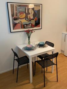 a white table with chairs and a painting on the wall at Tranquil studio near nature, free parking& wifi in Helsinki +3 photos