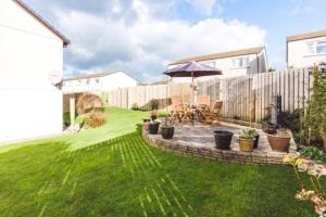 a garden with a patio and an umbrella at Scandi Style Home away from Home In Newquay in Newquay
