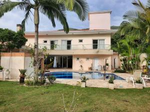 een huis met een zwembad en palmbomen bij Demi-suíte privativa em casa familiar 2 in Itajaí