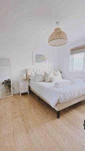 a white bedroom with two beds and a chandelier at Scandi Style Home away from Home In Newquay in Newquay