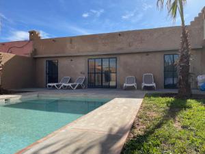 ein Haus mit einem Pool und zwei Stühlen in der Unterkunft Villa exclusive piscine privée proche centre in Marrakesch