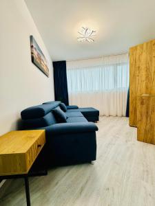 uma sala de estar com um sofá azul e uma mesa em Altheda Living Avanera 9B-144 em Suceava