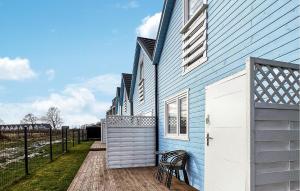 ein blaues Haus mit einem Stuhl auf einer Holzterrasse in der Unterkunft Cozy Home In Rewal With Outdoor Swimming Pool in Rewal