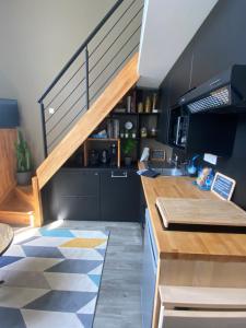 a kitchen with a staircase in the middle of a room at Une fenêtre sur l océan, Studio duplex dans résidence de standing avec piscine et vue sur mer in Le Croisic