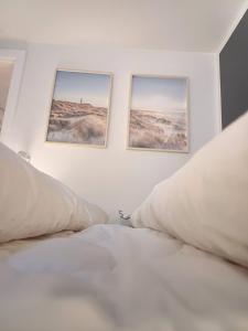 ein weißes Bett mit zwei Bildern an der Wand in der Unterkunft Elegant Apartment In Central Aalborg in Aalborg