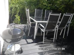 eine Gruppe von Stühlen und einem Grill auf einer Terrasse in der Unterkunft Maison moderne pour 4- 5 personnes in Sulniac