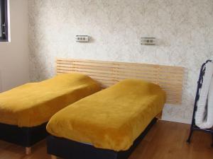 2 Betten mit gelben Decken in einem Zimmer in der Unterkunft Maison moderne pour 4- 5 personnes in Sulniac
