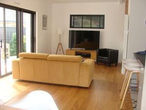ein Wohnzimmer mit einem Sofa und einem Flachbild-TV in der Unterkunft Maison moderne pour 4- 5 personnes in Sulniac