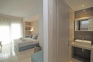 a bedroom with a bed and a bathroom with a sink at EL MARE ROOMS in Pefkohori