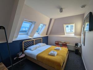 a bedroom with a bed with yellow sheets and two windows at Hotel 1851 in Wijk bij Duurstede