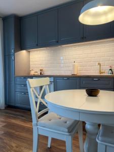 une cuisine avec des armoires bleues, une table blanche et une chaise dans l'établissement RINO, à Klis