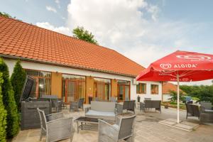 a patio with an umbrella and chairs and a building at Koma Vendégház in Aporliget
