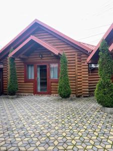 een blokhut met een rode deur en twee bomen bij Hotel Ashad in Svaliava