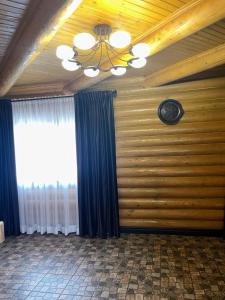 a room with a wooden wall with a chandelier and a window at Hotel Ashad in Svalyava