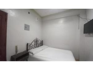 een witte slaapkamer met een bed en een televisie bij OYO 1066 Dorotello Apartelle in Manilla