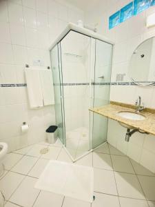 uma casa de banho com uma cabina de duche em vidro e um lavatório. em Hotel Palmar no Guarujá